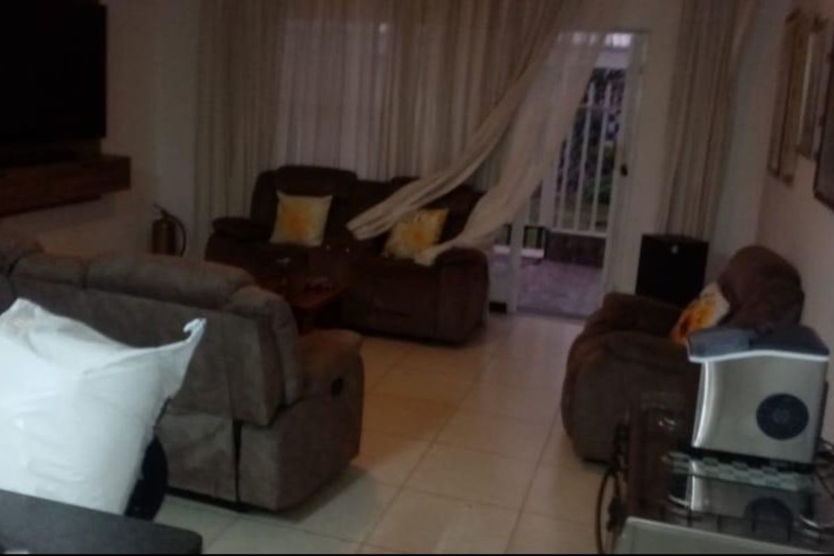 A living room area featuring tiled flooring and direct access to an outdoor space through a sliding glass door.