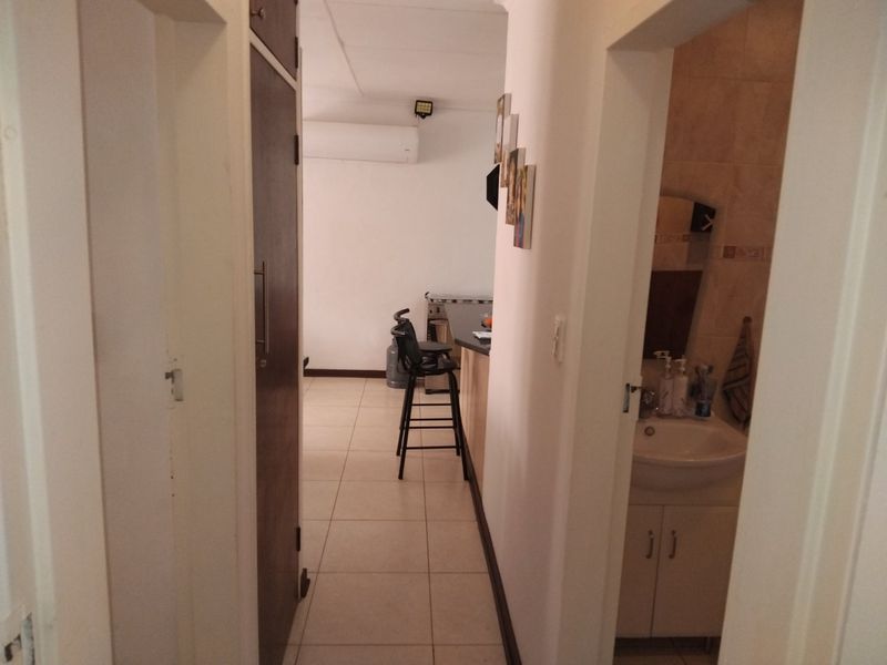 A view from the hallway looking towards the kitchen area, with a glimpse of the adjacent bathroom featuring a vanity and basin.