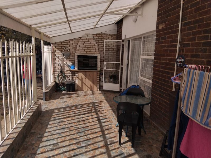 Covered patio area featuring a built-in braai, tiled flooring, and a translucent roof, providing a functional outdoor entertainment space.
