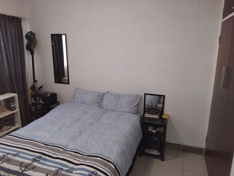 A functional bedroom featuring tiled flooring and a built-in wardrobe, providing a practical living space.