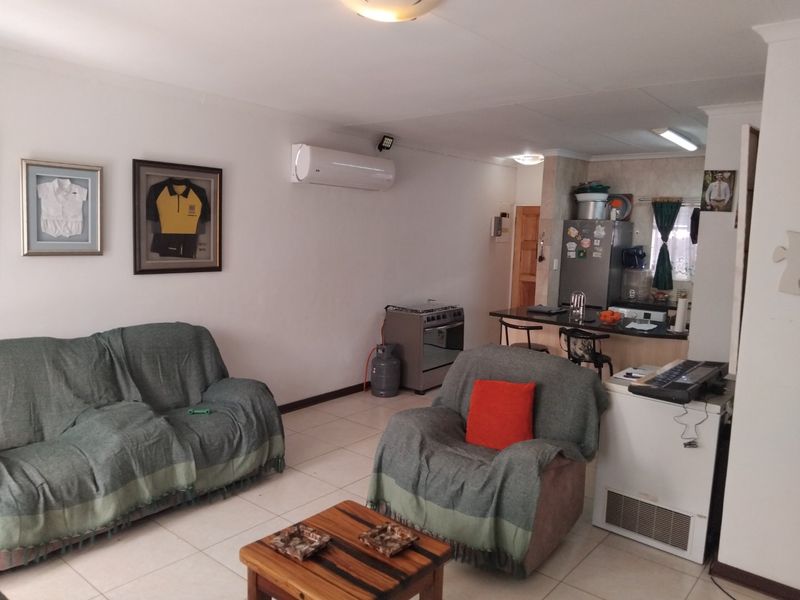 Open-plan living area featuring tiled flooring, a split-system air conditioner, and a functional kitchen with a breakfast bar.