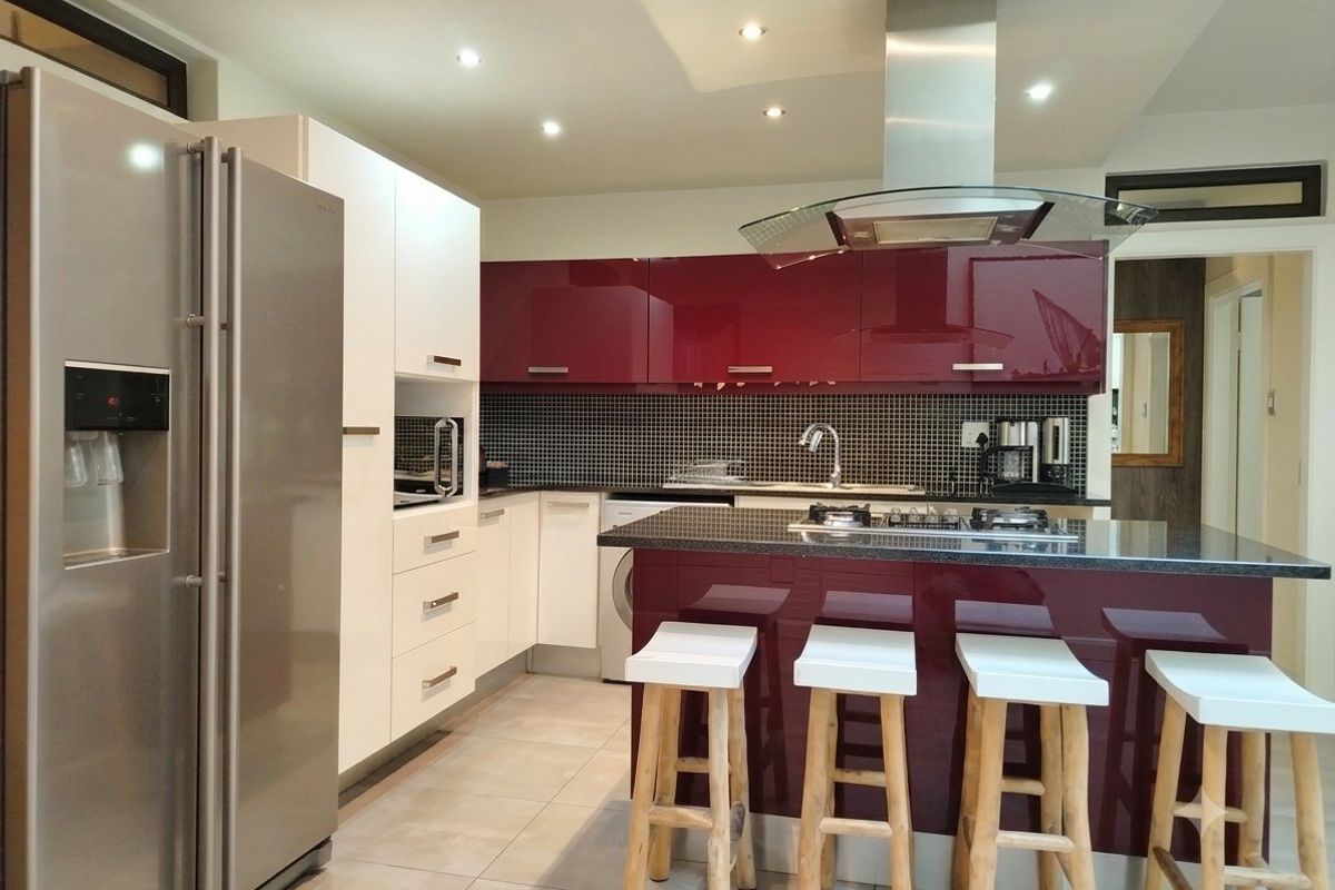 Modern kitchen featuring high-gloss cabinetry, a central island with a gas hob, mosaic tile backsplash, and integrated stainless steel appliances.
