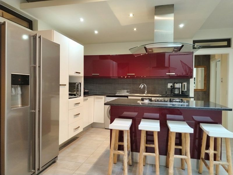 Modern kitchen featuring high-gloss cabinetry, a central island with a gas hob, mosaic tile backsplash, and integrated stainless steel appliances.