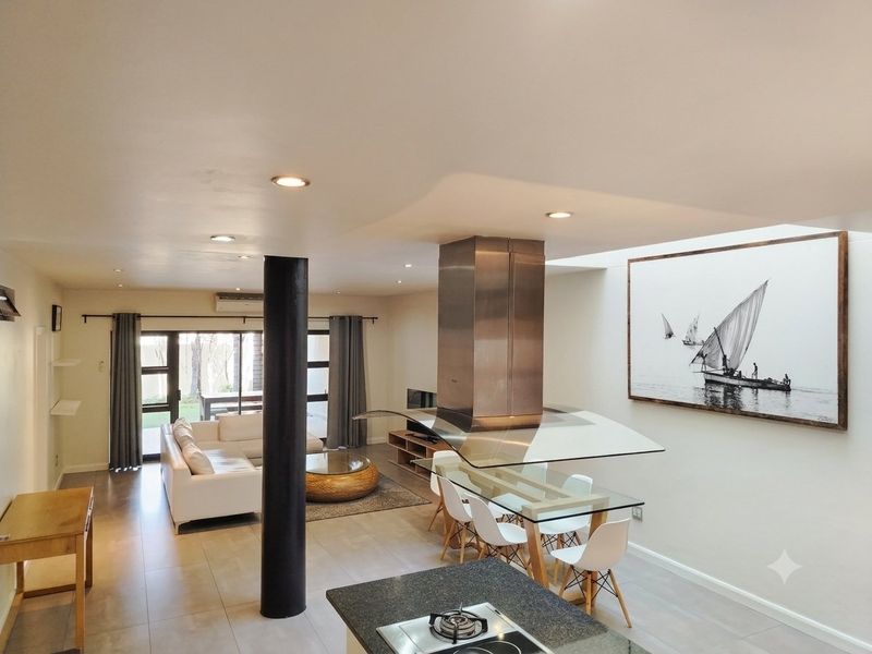 Spacious open-plan living and dining area featuring a modern kitchen island with gas hob, stainless steel extractor, and direct access to the patio.