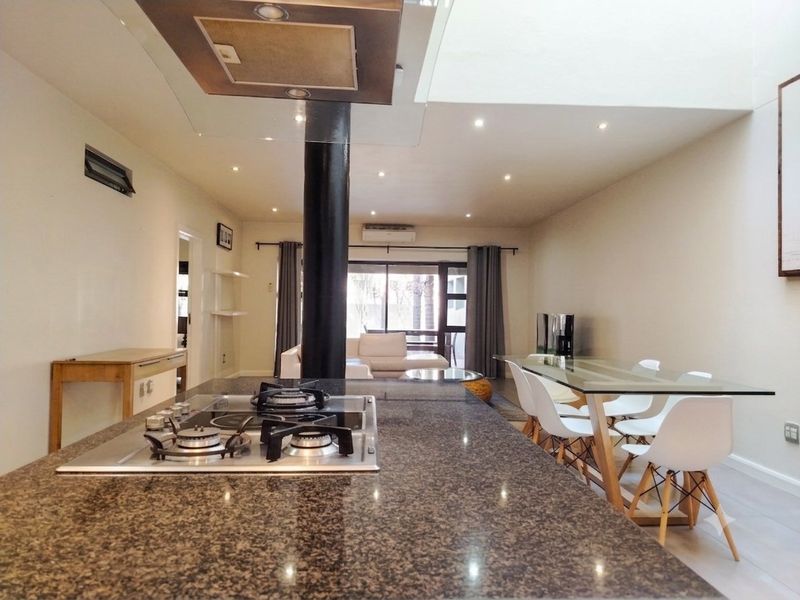Spacious open-plan living and dining area featuring a large granite kitchen island with a built-in gas hob and modern recessed lighting.