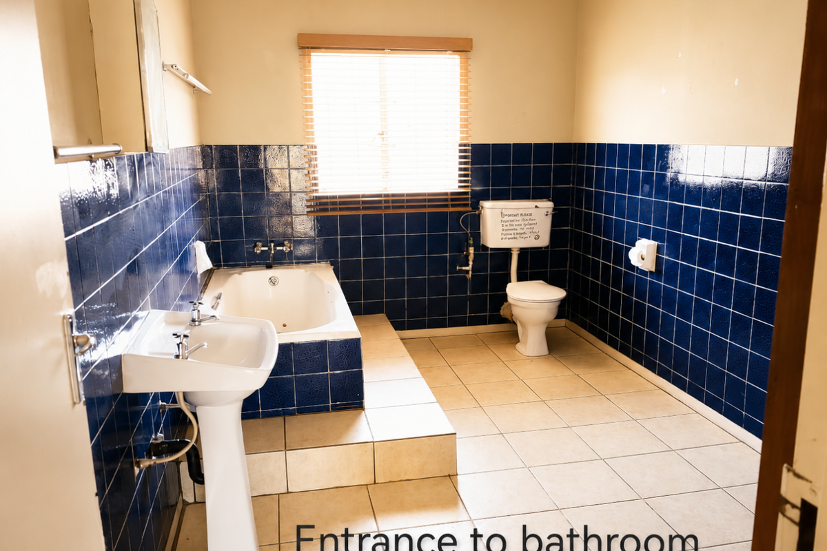 A dated bathroom featuring a pedestal basin, built-in bathtub, and toilet, finished with dark blue wall tiles and light floor tiles.