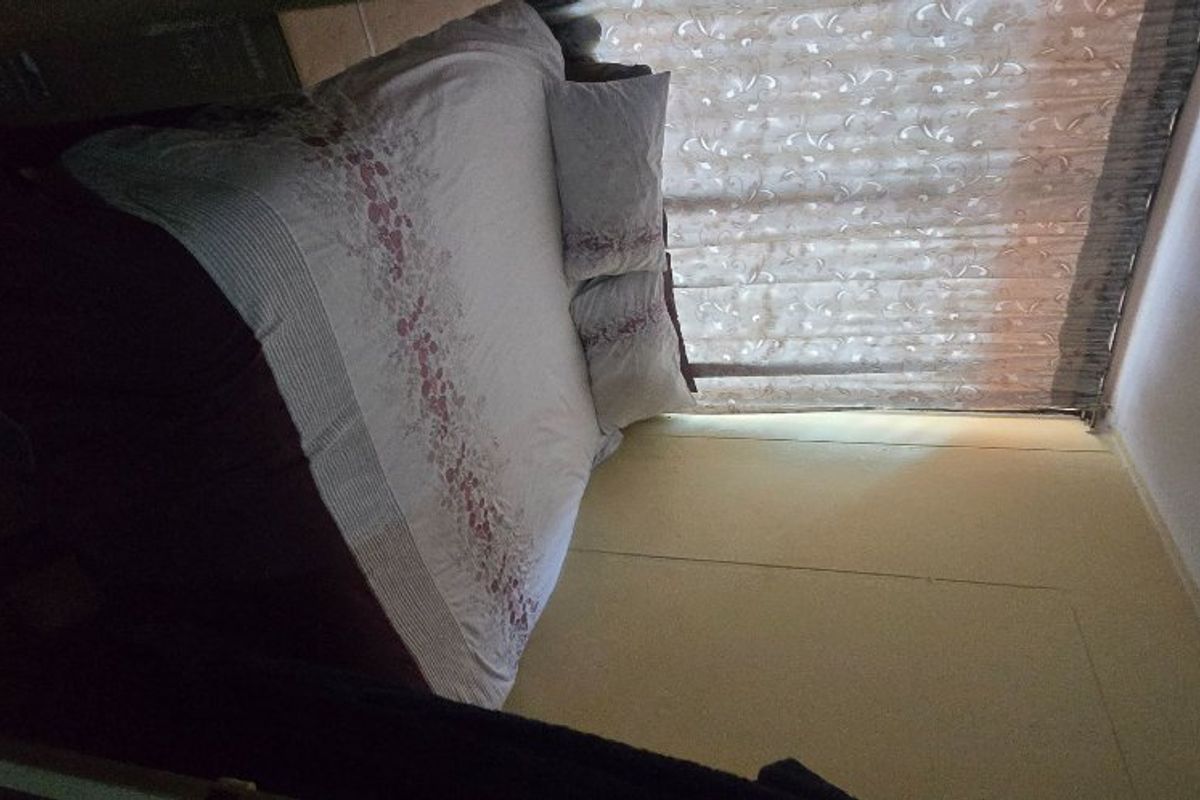 A bedroom featuring a window with curtains and a basic light fixture.