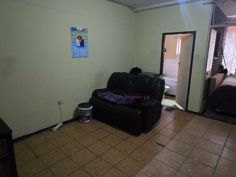 A living area featuring tiled flooring and an internal doorway leading to a bathroom, with an adjacent view into a bedroom space.