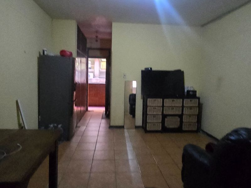 A living area featuring tiled flooring and built-in storage, providing a functional space with potential for modernization.