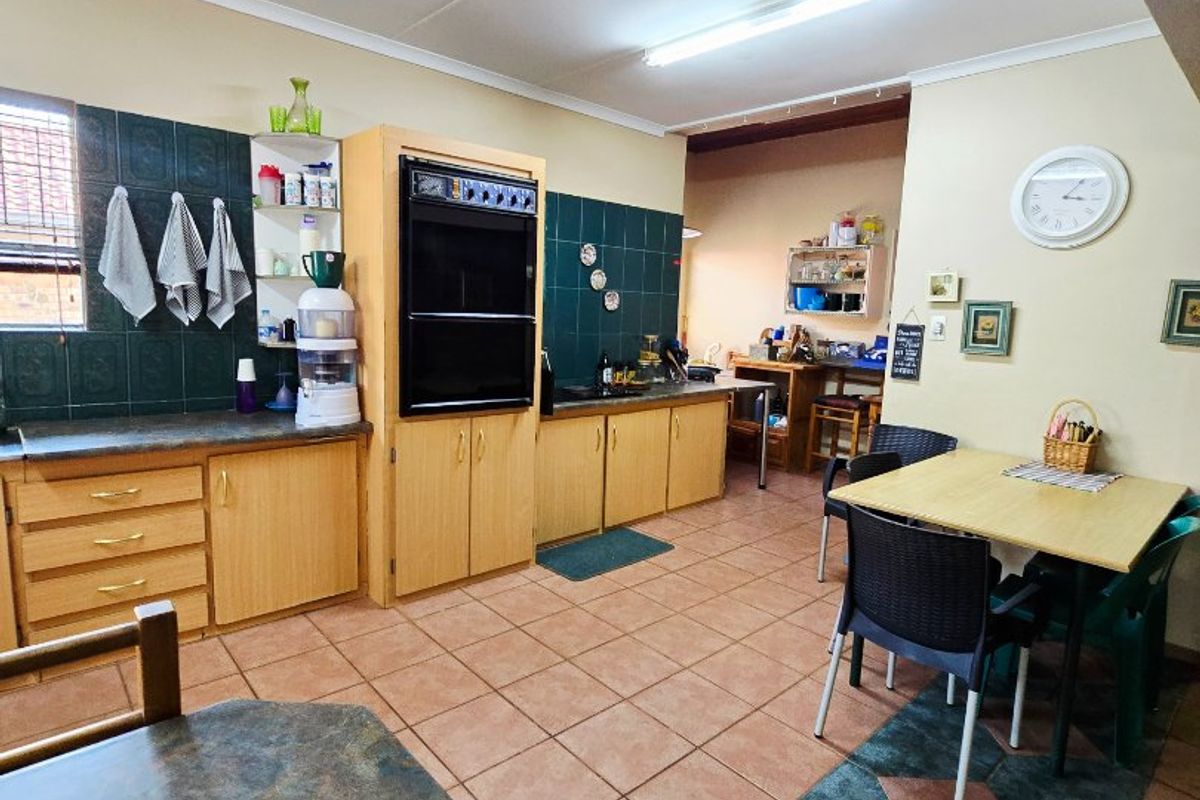 A functional kitchen featuring built-in oven, laminate cabinetry, and tiled flooring, offering a practical layout with an adjacent dining area.