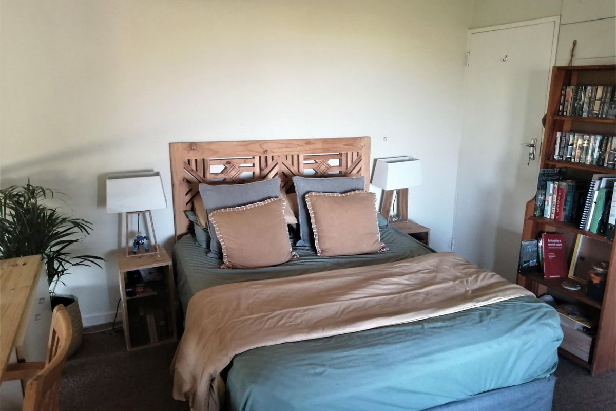 A functional bedroom featuring neutral wall finishes and a built-in cupboard, providing a comfortable and practical sleeping space.