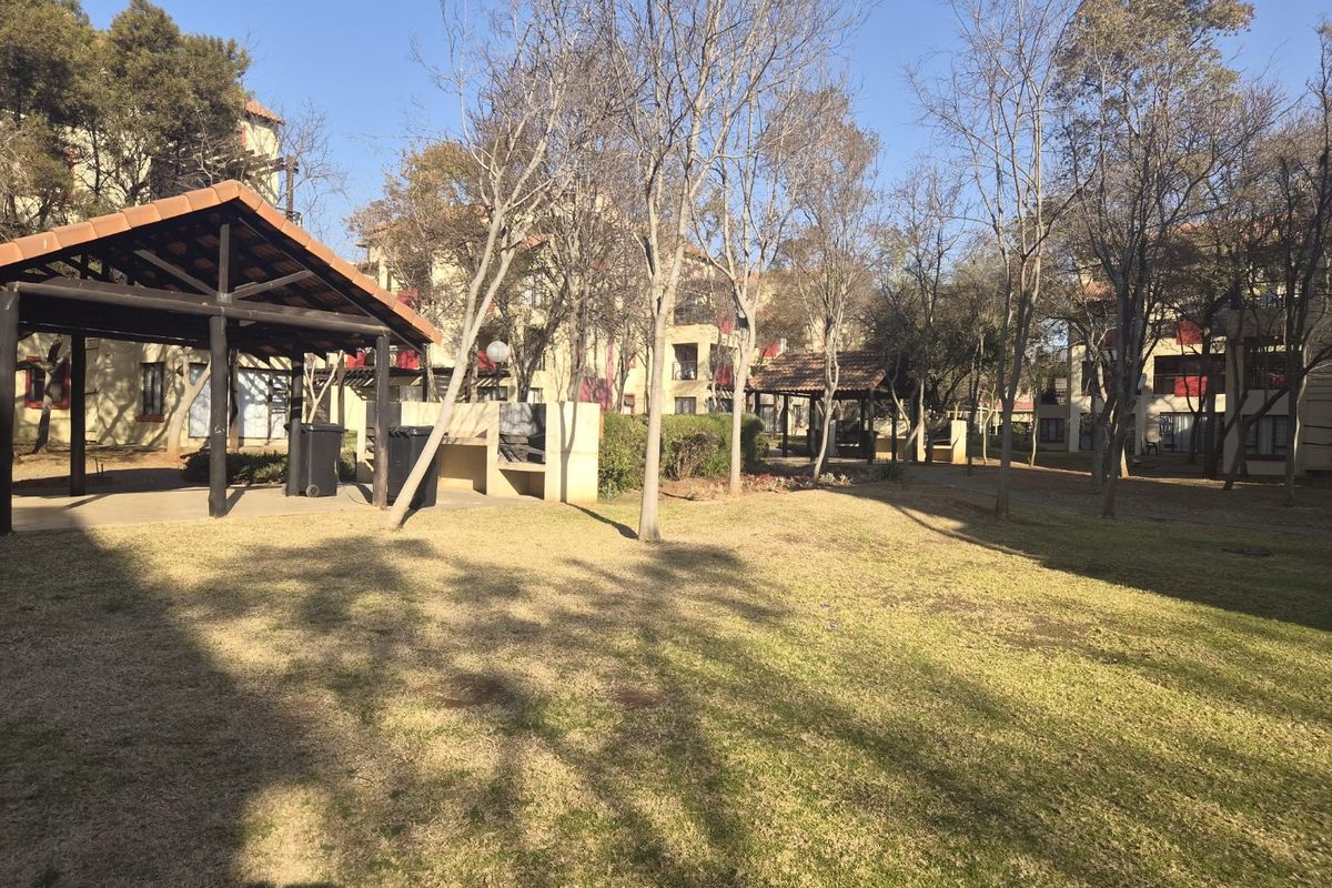 Communal garden area featuring a covered gazebo and built-in braai facilities within the apartment complex grounds.