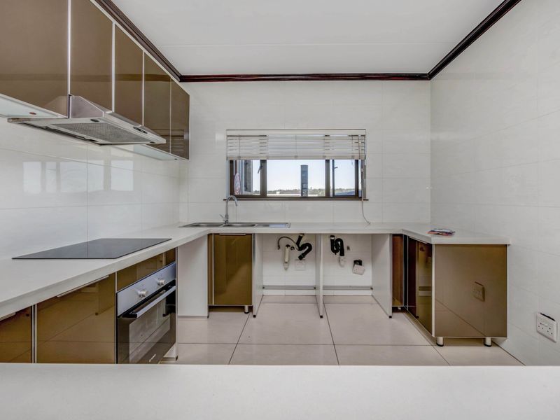 A functional kitchen featuring modern cabinetry, stone countertops, integrated oven and hob, and tiled finishes throughout. Requires minor cabinetry repairs under the sink.