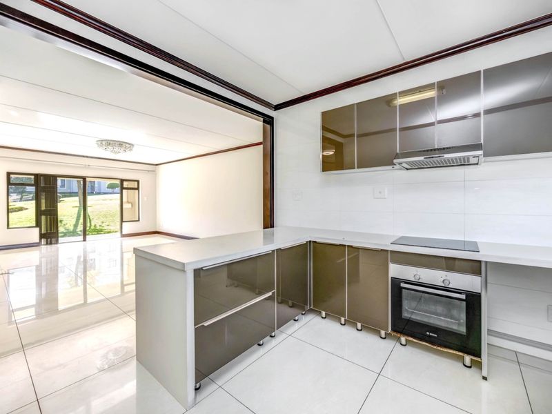 Open-plan kitchen and living area featuring modern cabinetry, built-in appliances, tiled flooring, and large sliding doors leading to an outdoor space.