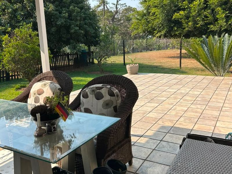 A covered outdoor patio area featuring tiled flooring and views over the garden.