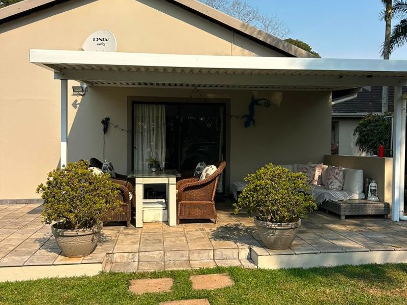 A well-maintained covered patio area featuring tiled flooring and direct access to the garden through sliding glass doors.