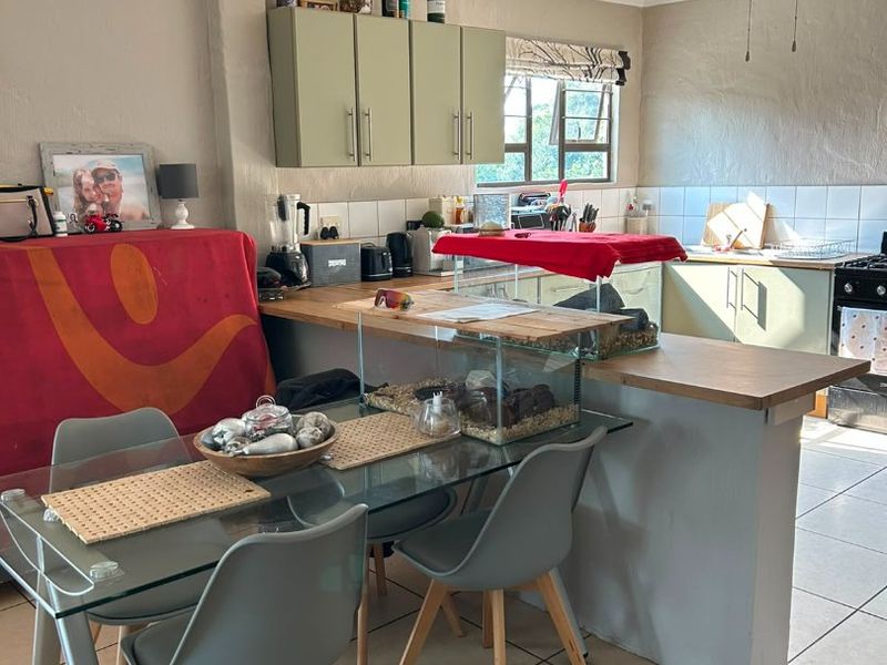 Open plan kitchen and dining area featuring tiled flooring, breakfast bar, and neutral cabinetry, offering a functional layout for daily living.