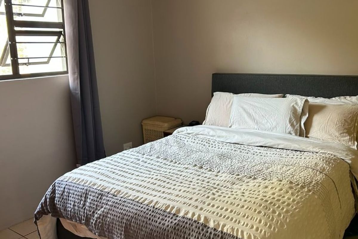 A functional bedroom featuring tiled flooring and a louvered window, providing a neutral space ready for personalization.