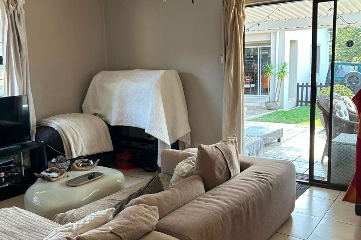 A living room featuring tiled flooring, a ceiling fan, and a sliding glass door providing direct access to an outdoor patio area.