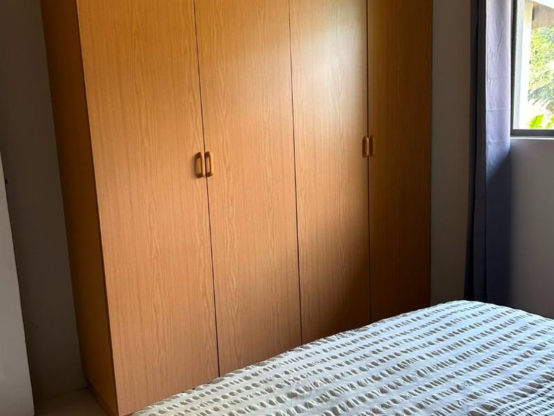 A bedroom featuring a large, full-height built-in wooden wardrobe and tiled flooring, providing ample storage space.