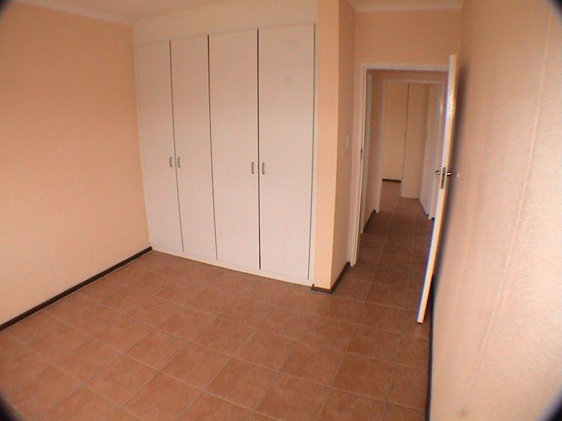 An empty bedroom featuring built-in cupboards and tiled flooring, providing a neutral space ready for personalization.