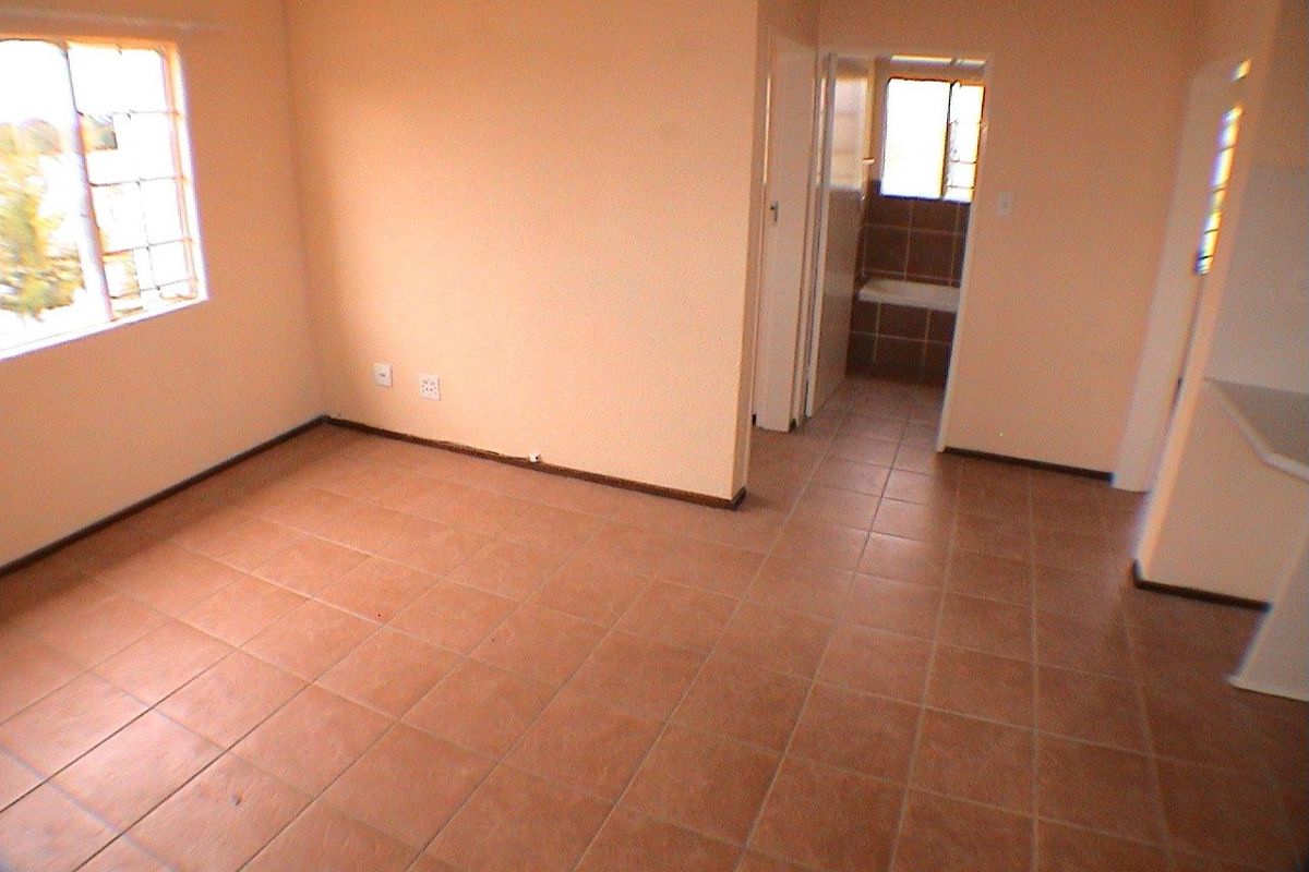 An empty living area featuring tiled flooring and access to an adjacent bathroom, providing a blank canvas for renovation or interior design.