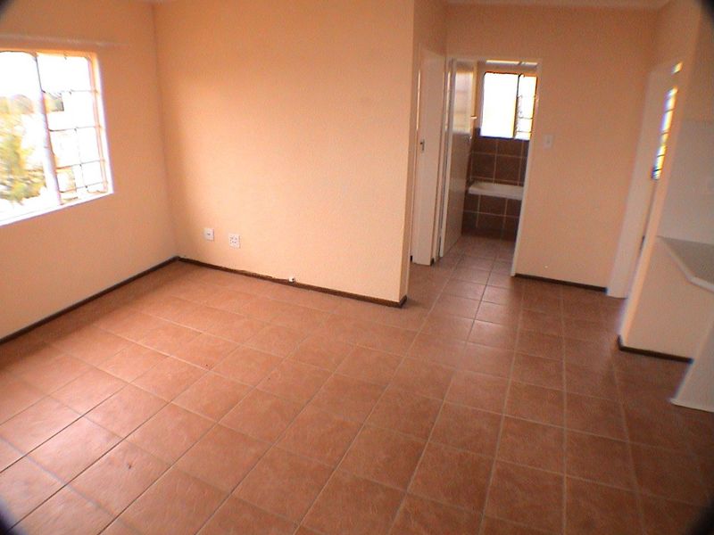 An empty living area featuring tiled flooring and access to an adjacent bathroom, providing a blank canvas for renovation or interior design.