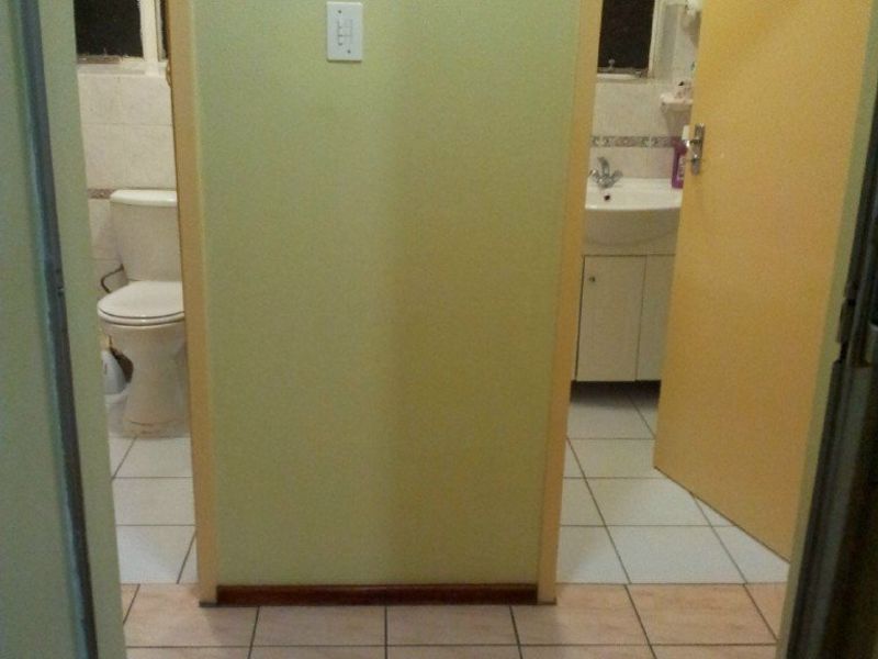 A hallway providing access to two separate bathroom areas, featuring tiled flooring and standard internal door frames.