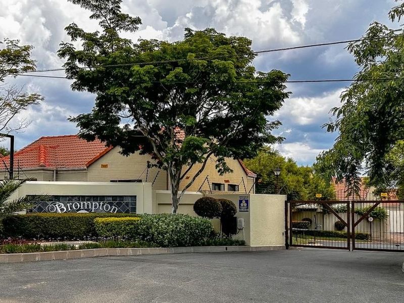 The entrance to Brompton complex featuring a secure gated access point, perimeter wall with electric fencing, and well-maintained landscaping.
