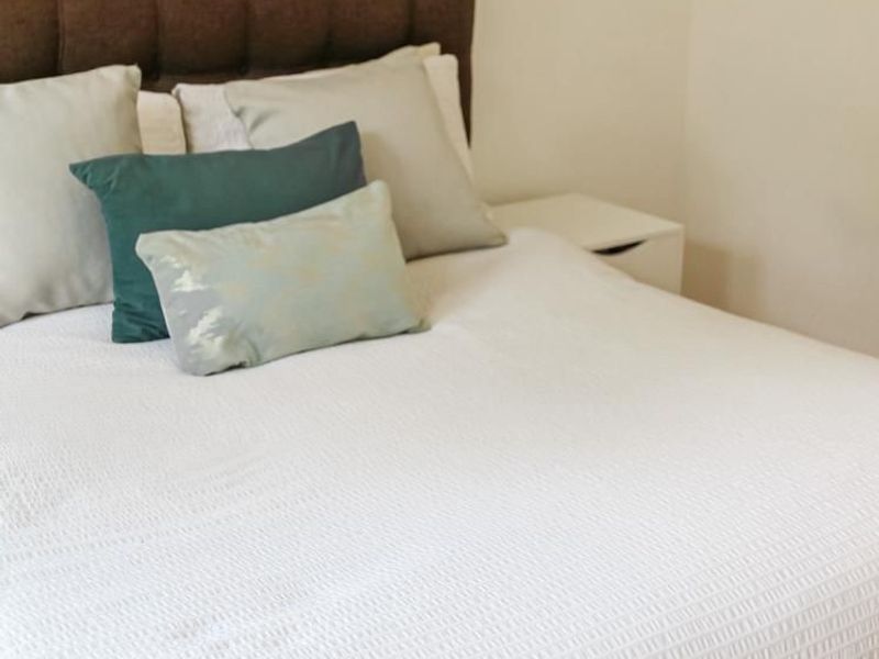 A well-maintained bedroom featuring a neutral color palette and a tufted headboard.