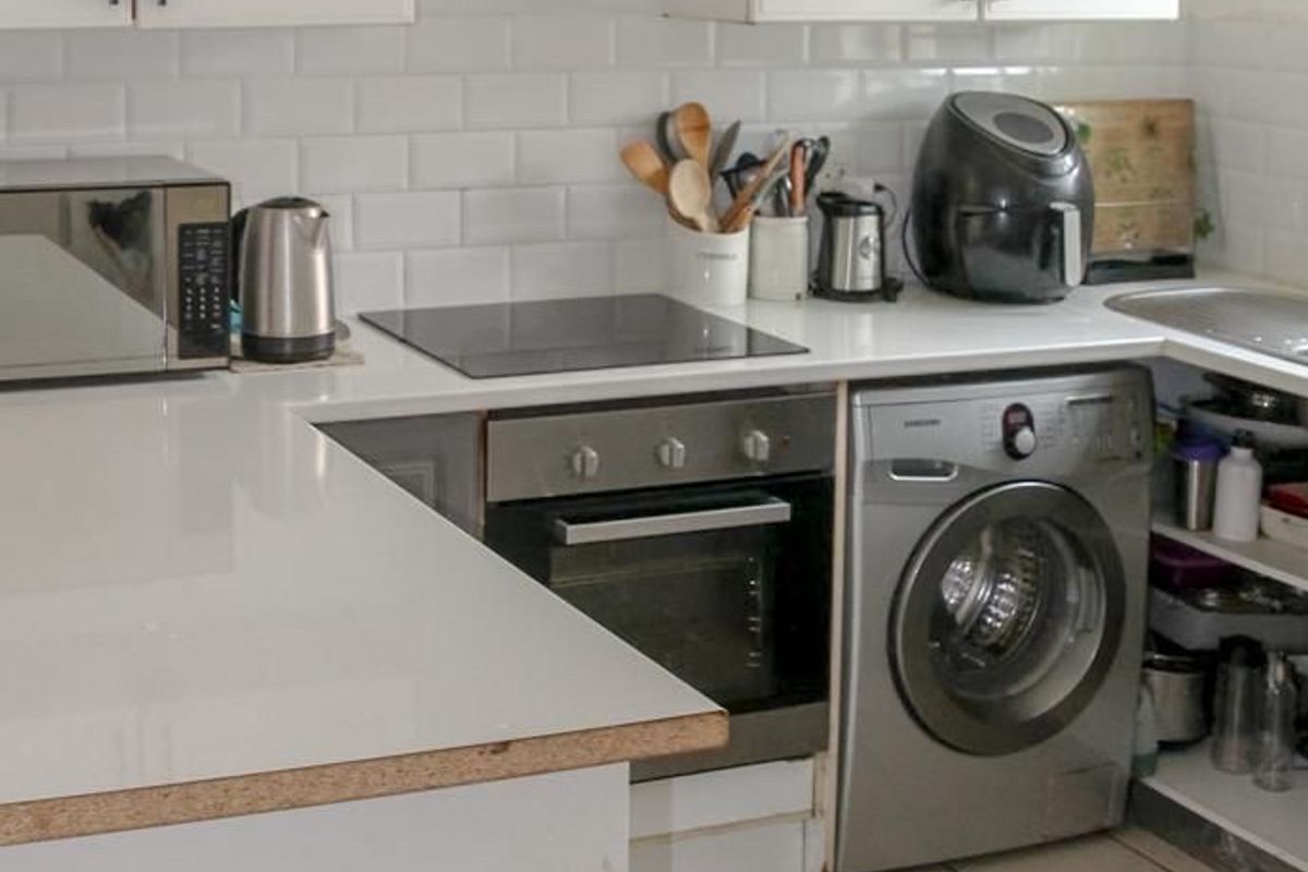 Compact kitchen featuring white cabinetry, subway tile backsplash, built-in oven, electric cooktop, and tiled flooring.