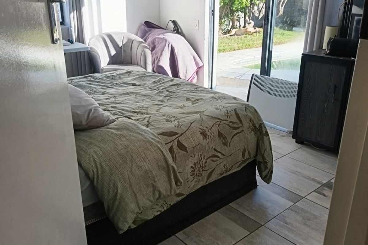 A bedroom featuring ceramic floor tiles and a sliding glass door providing direct access to the outdoor pool area.