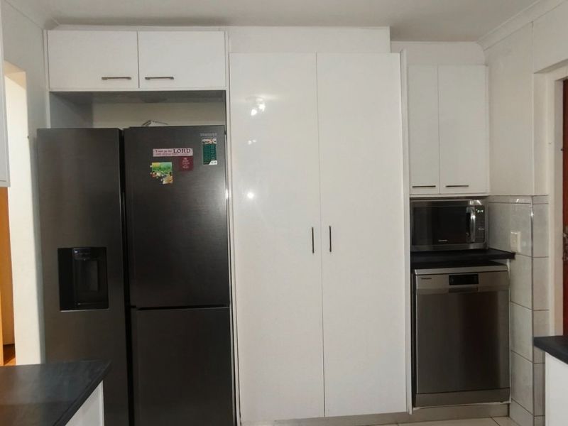 A functional kitchen featuring white cabinetry, dark countertops, and integrated appliances, providing a clean and practical workspace.