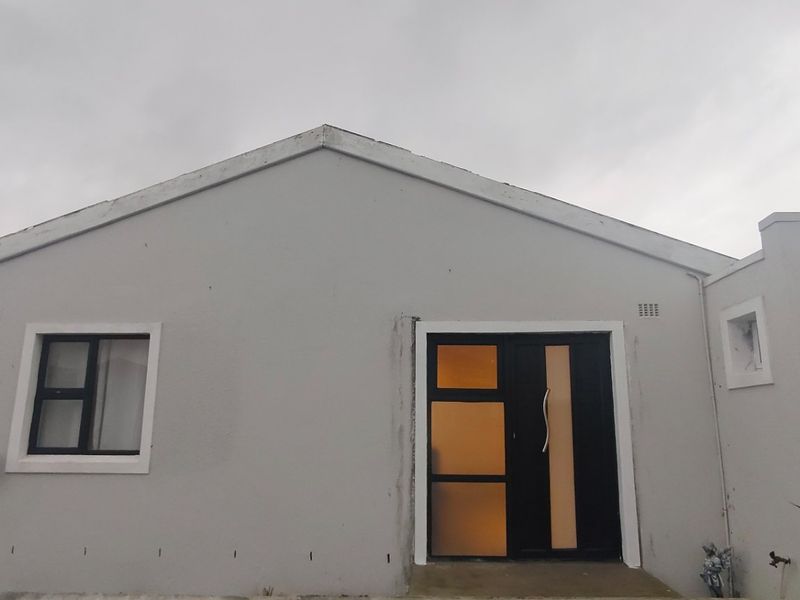 Front elevation of a residential house featuring a modern entrance door and aluminium window frames under a gabled roofline.