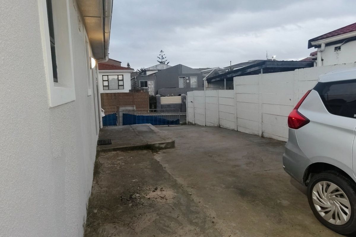 A view of the rear exterior area featuring a concrete driveway and boundary walling.