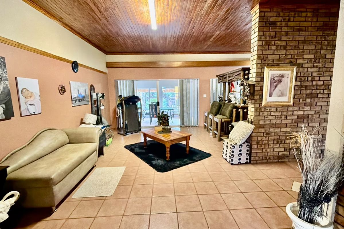 Spacious living room featuring a prominent exposed brick fireplace, timber ceiling, and large sliding glass doors leading to the outdoor area.