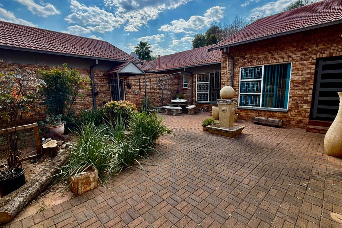 A private rear courtyard featuring facebrick walls, tiled roofing, and paved flooring with a central stone water feature.