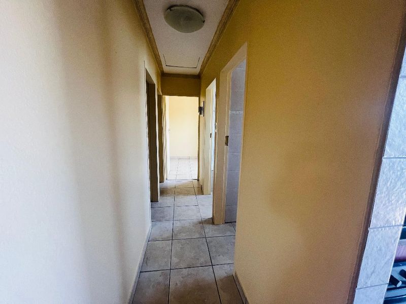 A functional hallway featuring neutral wall tones and tiled flooring, providing access to multiple rooms within the home.