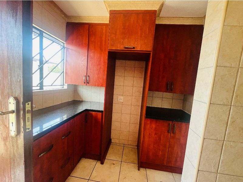 A functional kitchen featuring dark wood-look cabinetry, granite countertops, and tiled finishes, offering a practical layout ready for modernization.