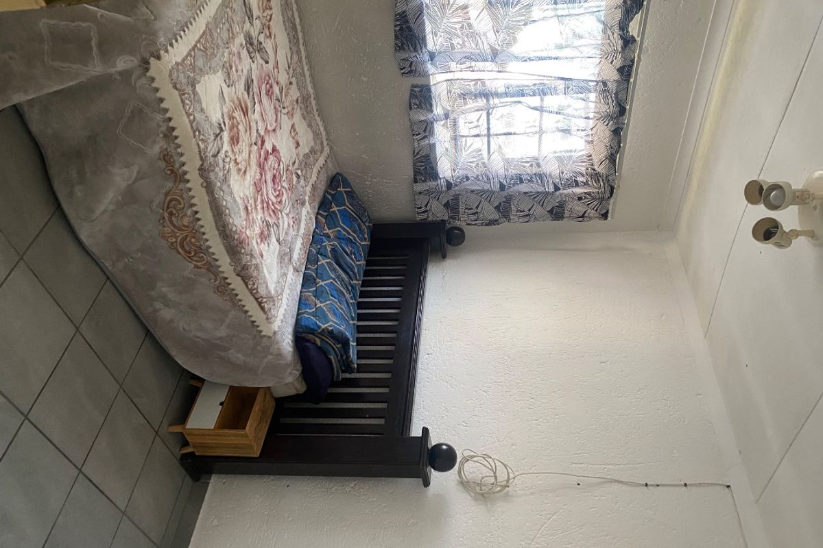 A bedroom featuring tiled flooring and textured walls, currently requiring maintenance due to visible exposed wiring and dated finishes.