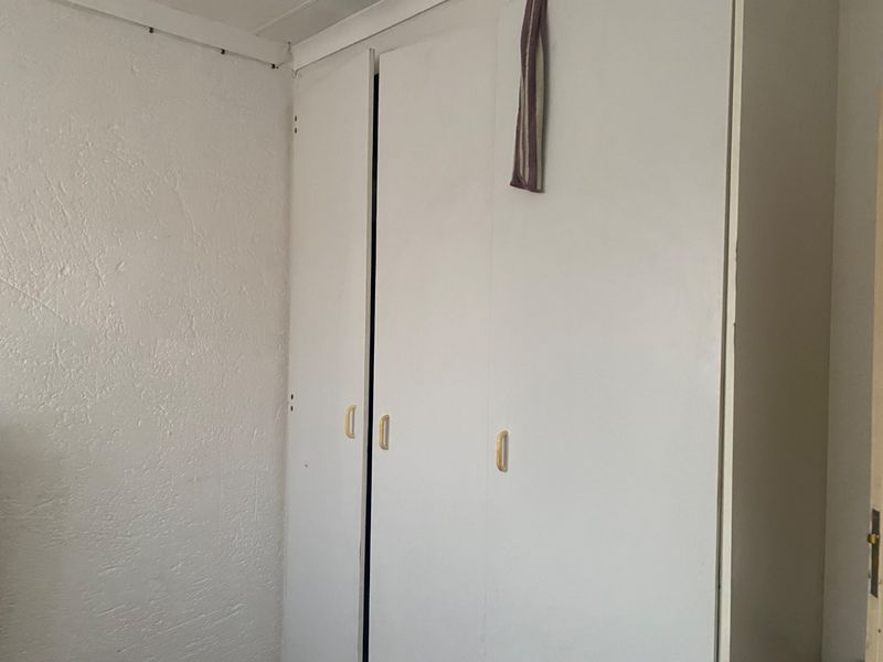 A bedroom featuring a built-in wardrobe with white doors and simple handles, set against a textured wall.