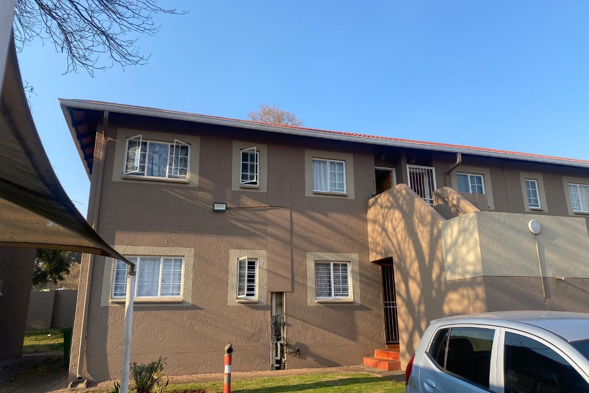 Rear elevation of a multi-story apartment building featuring tiled roofing, security-fitted windows, and external access stairs.