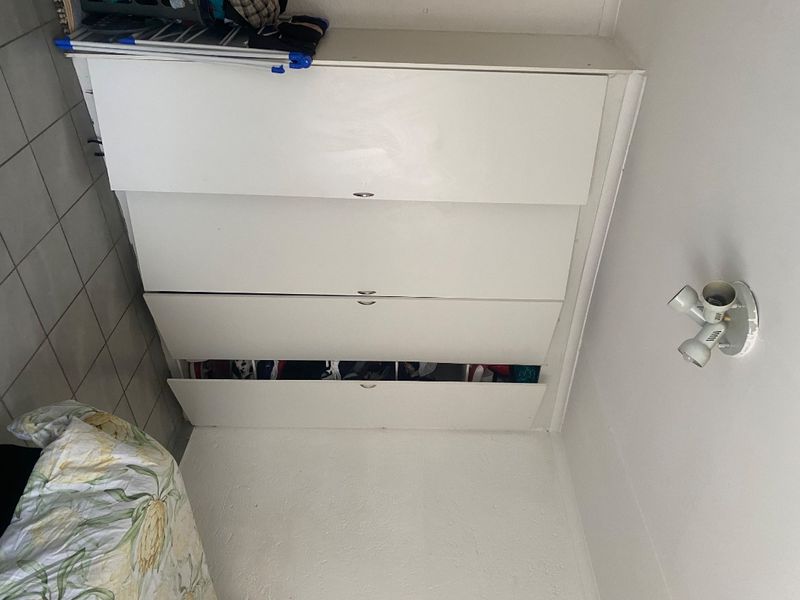 A bedroom featuring a built-in white wardrobe with multiple storage compartments and tiled flooring.