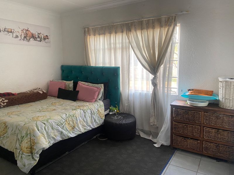 A bedroom featuring tiled flooring and a window with curtains, providing a functional space for rest.