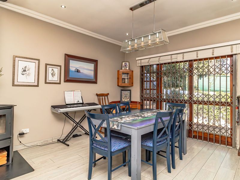 Dining area featuring a freestanding fireplace, laminate flooring, crown molding, and sliding glass doors with security gates leading to the exterior.