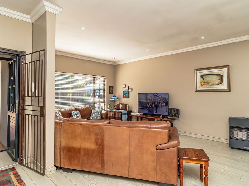 Spacious living room featuring a modern freestanding fireplace, recessed lighting, and neutral tiled flooring, with an adjacent view into the kitchen area.