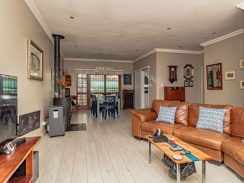 Spacious open-plan living and dining area featuring light-toned laminate flooring, a central freestanding fireplace, and direct access to the outdoor area via sliding doors.