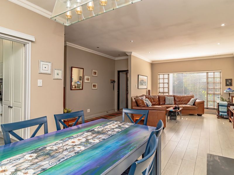 Spacious open-plan living and dining area featuring laminate flooring, recessed lighting, and a cozy wood-burning stove, with an adjacent kitchen visible through sliding doors.