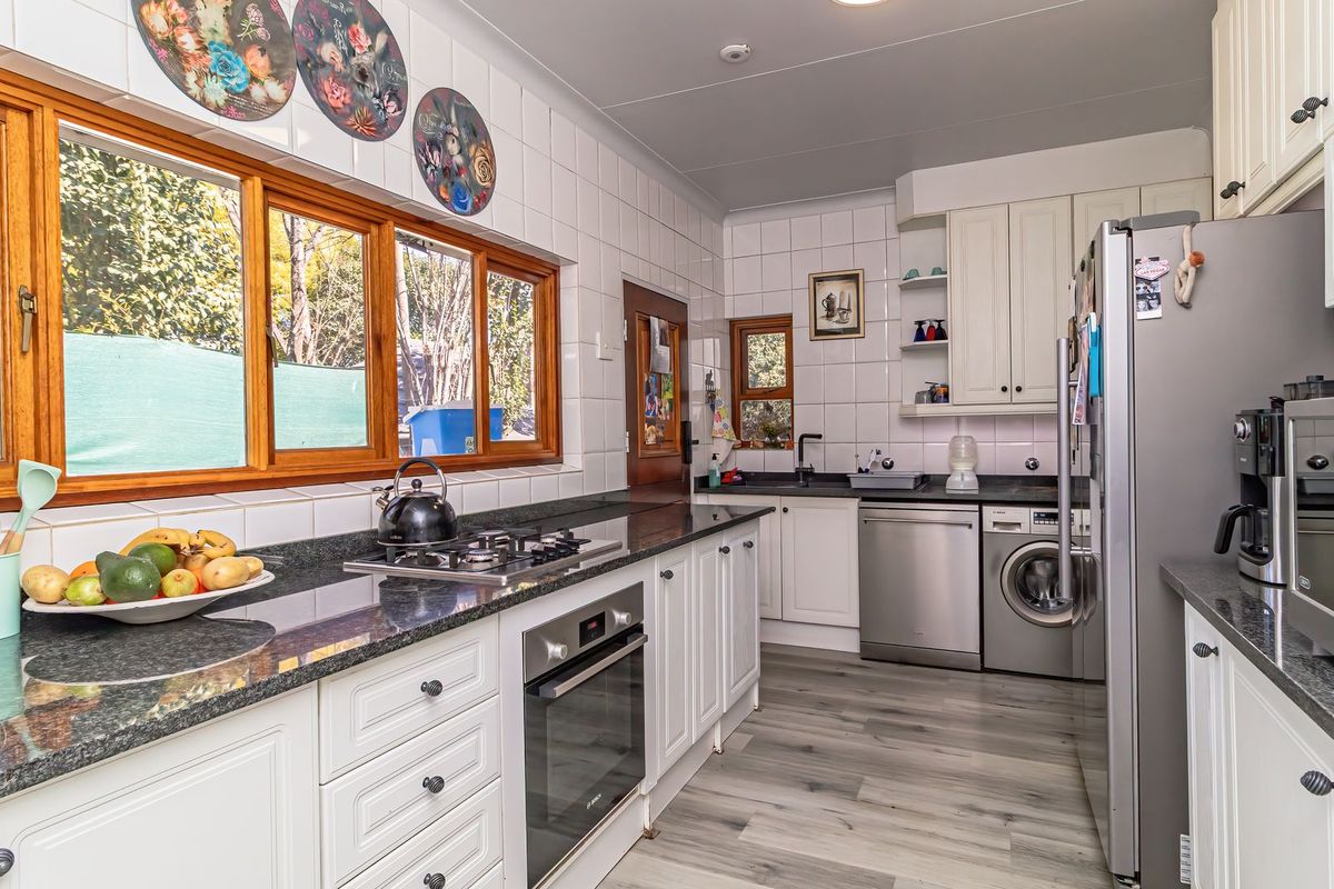 A well-maintained kitchen featuring granite countertops, built-in oven, gas hob, and ample cabinetry with a bright, functional layout.