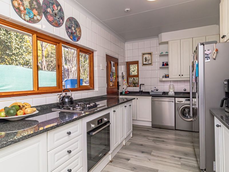 A well-maintained kitchen featuring granite countertops, built-in oven, gas hob, and ample cabinetry with a bright, functional layout.